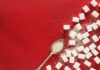 “혈당 스파이크 잡는 법: 건강하고 맛있는 생활습관 팁” sugar cubes and a spoon on a red surface