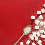 “혈당 스파이크 잡는 법: 건강하고 맛있는 생활습관 팁” sugar cubes and a spoon on a red surface