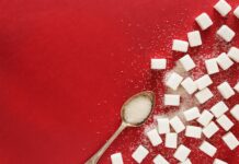 “혈당 스파이크 잡는 법: 건강하고 맛있는 생활습관 팁” sugar cubes and a spoon on a red surface